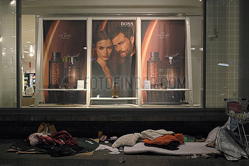 Deutschland  Berlin - Utensilien von Obdachlosen vor Schaufenster von Karstadt mit Werbefoto fuer Parfuem der Edelmarke Boss