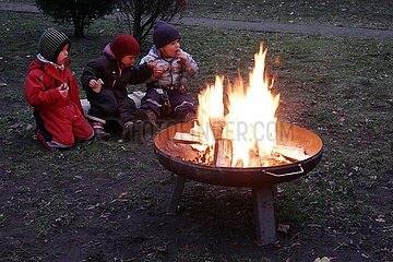 Berlin  Deutschland  Kleinkinder sitzen an einer Feuerschale