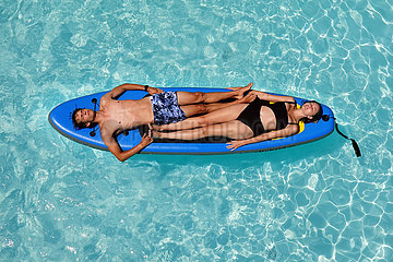 Bolsena  Italien  junges Paar liegt in einem Swimmingpool auf einem SUP-Board