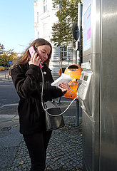 Berlin  Deutschland  Frau telefoniert an einer oeffentlichen Telefonstele der Telekom