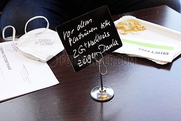 Rostock  Deutschland  Schild auf einem Tisch: Bitte vor dem Platzieren 2G+ Nachweis zeigen