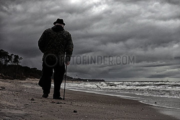 Ustka  Polen  Senior laeuft bei Schlechtwetter am Strand entlang