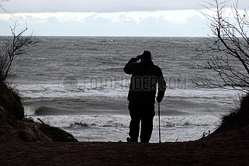 Ustka  Polen  Silhouette: Senior laeuft bei Schlechtwetter zum Strand hinunter