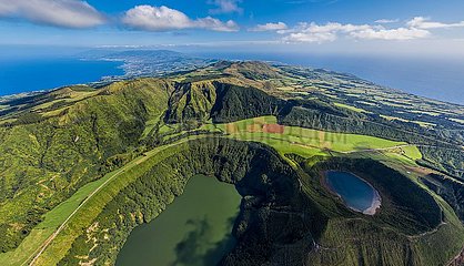 Portugal. Azores-Inseln  Luftbild der Insel Sao Miguel (die touristischste des Archipels) mit seinen Sete Cidades  einem vulkanischen Krater 12 km im Umfang  der von seinem Gipfel an der Vista do Rei Belvedere entdeckt wird. Schlafen Sie unten die transparenten Gewässer seines grünen Sees und des blauen Seees. Der See wurde in der Mulde der Berge in der Mitte der Insel gebildet  nach einem vulkanischen Ausbruch im 16. Jahrhundert. Ein beeindruckender Pfad geht um den Krater
