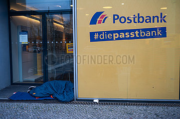 Berlin  Deutschland  Ein Obdachloser schlaeft auf dem Boden vor einer Filiale der Postbank