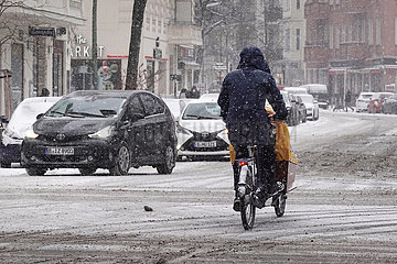 Berlin  Deutschland  Radfahrer faehrt bei heftigem Schneefall auf einer Strasse