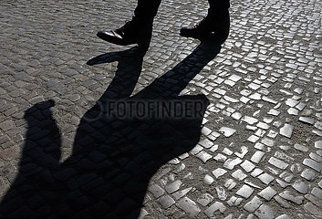 Berlin  Deutschland  Mann wirft beim Gehen einen Schatten auf Kopfsteinpflaster
