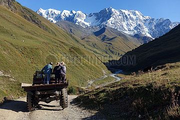 Adishi  Georgien  Maenner fahren in einem Tal auf der Ladeflaeche eines LKW
