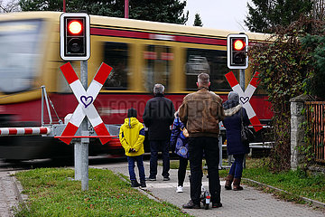 Neuenhagen  Deutschland  Menschen warten an einem beschrankten Bahnuebergang auf die Durchfahrt der S-Bahn