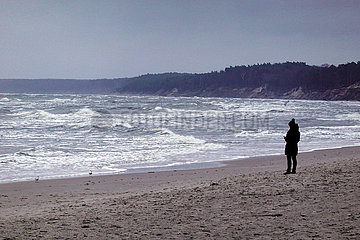 Ustka  Polen  Frau steht allein am Strand der stuermischen Ostsee