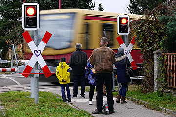 Neuenhagen  Deutschland  Menschen warten an einem beschrankten Bahnuebergang auf die Durchfahrt der S-Bahn
