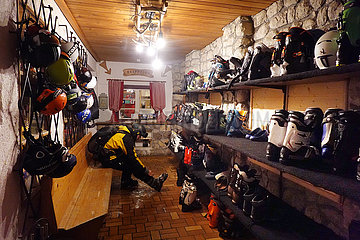 Obertraun  Oesterreich  Skifahrer zieht sich vor der Rezeption der Gjaid Alm um