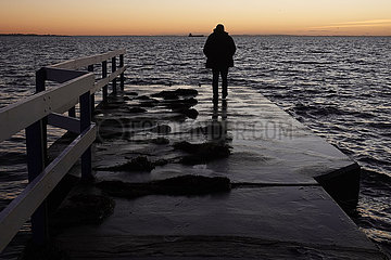 Helsingborg  Schweden  Silhouette: Mann laeuft allein am Abend auf einem Bootsanleger entlang