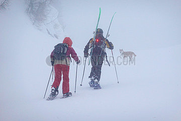 Obertraun  Oesterreich  Mann und Frau machen bei heftigem Schneefall eine Schneeschuhwanderung