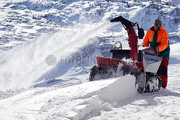 Obertraun  Oesterreich  Mann befreit eine Skipiste mit einer Schneefraese vom Neuschnee