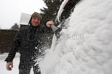 Berlin  Deutschland  Mann fegt frisch gefallenen Schnee von seinem Auto