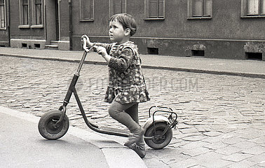 Ost-Berlin  Deutsche Demokratische Republik  kleines Maedchen ueberquert allein mit ihrem Roller eine Strasse