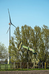Deutschland  Barenburg - Erdoelproduktionsbohrung von Exxon Mobil mit einer Pferdekopfpumpe  hinten ein Windrad
