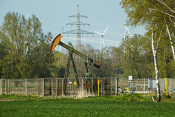 Deutschland  Barenburg - Erdoelproduktionsbohrung von Exxon Mobil mit einer Pferdekopfpumpe  hinten Windraeder und Strommast