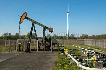 Deutschland  Barenburg - Erdoelproduktionsbohrung von Exxon Mobil mit einer Pferdekopfpumpe  hinten ein Windrad