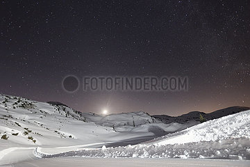 Obertraun  Oesterreich  Sternenhimmel leuchtet in der Nacht bei Vollmond in den schneebedeckten Alpen