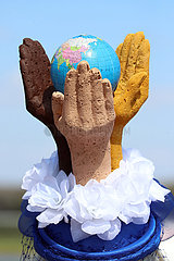 Magdeburg  Deutschland  Hutkreation: Haende verschiedener Hautfarben umfassen einen Globus