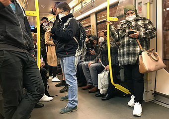 Berlin  Deutschland  Menschen fahren in Zeiten der Coronapandemie mit FFP2-Masken U-Bahn und schauen auf ihre Mobiltelefone