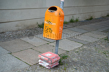 Berlin  Deutschland  Leere und weggeworfene Pizzakartons liegen neben einem Muelleimer auf dem Boden