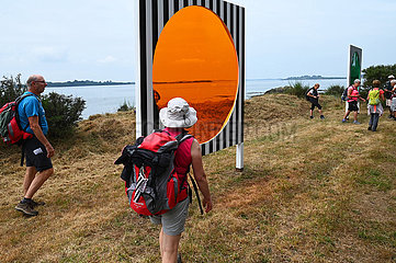 France. Brittany. Morbihan (56) Island of Arz. Bilherve. Group of tourists in front of one of the works of the ephemeral exhibition Au detour des routes et des chemins by the famous visual artist Daniel Buren  installed on the island until November 2023