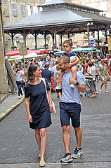 FRANCE. OCCITANY. LOT (46) FIGEAC. A YOUNG COUPLE AND THEIR CHILD ON MARKET DAY