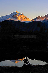 Savoie ( 73 )  Tignes  randonneur dans la reserve naturelle de la Grande Sassiere devant la Grande Motte en Tarentaise. Fin de journee pres d'un petit lac. La Grande Motte se reflete sur le plan d'eau. La randonneur est juste au bon endroit pour la creation d'une image equilibree sans fausse note