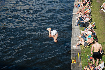Berlin  Deutschland  Junger Mann springt mit einem Rueckwaertssalto vom Ufer in die kuehle Spree