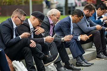 Deutschland  Hannover - Hannover-Messe  Geschaeftsleute aus unterschiedlichen Laendern sitzen konzentriert mit ihren smartfones