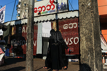 Yangon  Myanmar  Strassenszene mit Menschen vor Geschaeften zwischen Licht und Schatten