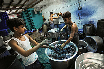 Mumbai  Indien  Arbeiter faerben Stoffe in einem Metallbottich in einer Werkstatt im Elendsviertel Dharavi