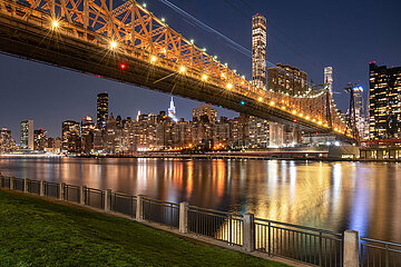 United States  New York City  Manhattan  Roosevelt Isalnd. Illuminated Queensborough Bridge spanning from the Upper East Side of Manhattan to Roosevelt Island. Evening view of New York City skyscrapers across the East River