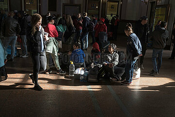 Lviv  Oblast Lviv  Ukraine - Auf ihrem Gepäck sitzend  wartet eine Familie in der Haupthalle des Hauptbahnhofes