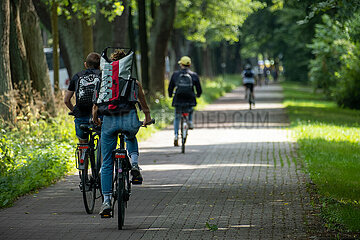 Deutschland  Bremen - Fahrradweg mit Fahrradfahrern an einer Strasse  rechts ein Park
