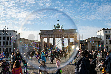 Berlin  Deutschland  Strassenkuenstler blaest Seifenblasen mit Schlaufen an einer Schnur vor dem Brandenburger Tor