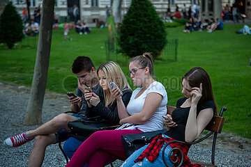 Kroatien  Zagreb - Jugendliche auf einer Parkbank vertieft in social media