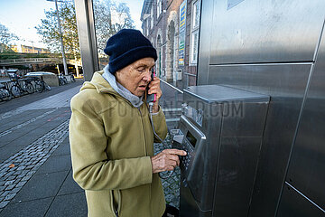Deutschland  Bremen - Ruestige Rentnerin waehlt eine Nummer an einer Telefonzelle der Deutschen Telekom
