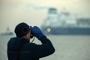 Deutschland  Wilhelmshaven - Mann mit Fernglas bei der Ankunft des norwegischen LNG-Tanker Hoeegh Esperanza am LNG-Terminal Wilhelmshaven