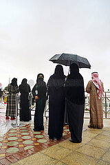 Riad  Saudi-Arabien  Arabische Frauen stehen bei Regen unter einem Regenschirm