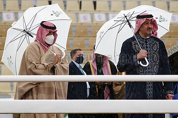 Riad  Saudi-Arabien  Arabische Maenner stehen bei Regen unter ihren Regenschirmen