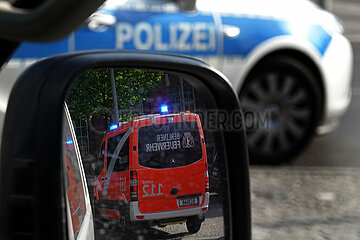Berlin  Deutschland  Notarztwagen der Berliner Feuerwehr spiegelt sich im Seitenspiegel eines PKW. Ein Einsatzfahrzeug der Polizei steht davor