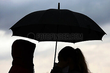 Leipzig  Deutschland  Silhouette: Menschen stehen bei Schlechtwetter unter einem Regenschirm