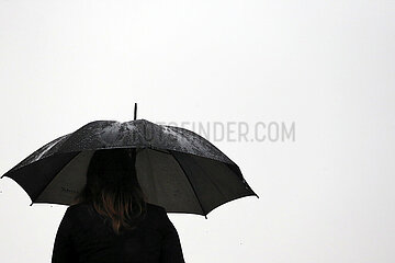 Leipzig  Deutschland  Frau steht bei Schlechtwetter unter einem Regenschirm