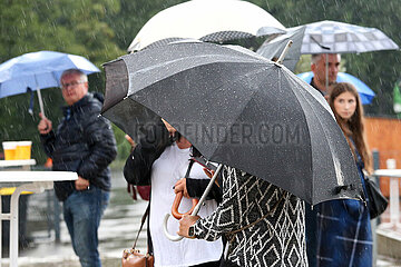 Leipzig  Deutschland  Menschen stehen bei Schlechtwetter unter ihren Regenschirmen
