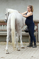 Bruchmuehle  Deutschland  schwangere Frau putzt ihr Pferd
