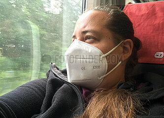 Berlin  Deutschland  Frau mit FFP2-Maske schaut bei einer Zugfahrt aus dem Fenster